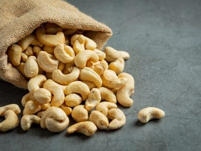 Raw cashews nuts in bag on dark background